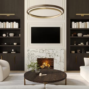 Puede incluir: Un interior de sala de estar con un sofá blanco, dos sillones blancos, una mesa de café, una chimenea y dos estanterías empotradas con acabados en madera oscura.