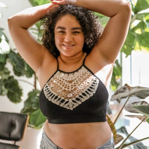 May include: A black bralette with a white crochet trim. The bralette has a halter neck style and is made of a soft, stretchy fabric.
