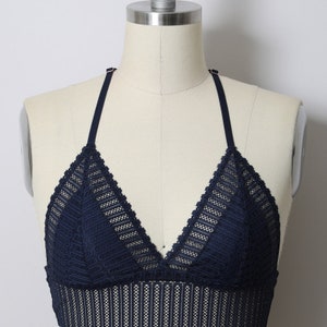 May include: A navy blue lace bralette with adjustable straps. The bralette has a triangle shape and a delicate lace pattern.