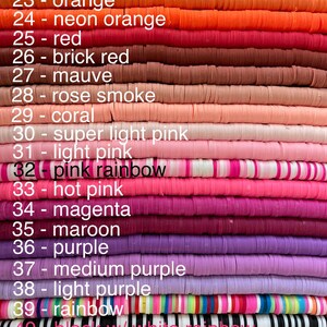 May include: A stack of colourful polymer clay beads, each bead is a different colour and has a number and colour name written next to it. The colours include yellow, orange, red, pink, purple, and brown.