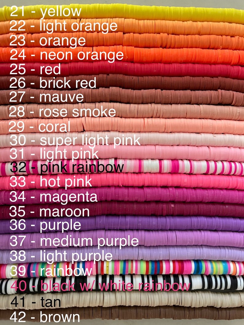 May include: A stack of colourful polymer clay beads, each bead is a different colour and has a number and colour name written next to it. The colours include yellow, orange, red, pink, purple, and brown.
