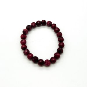 May include: A red and pink beaded bracelet with round beads.