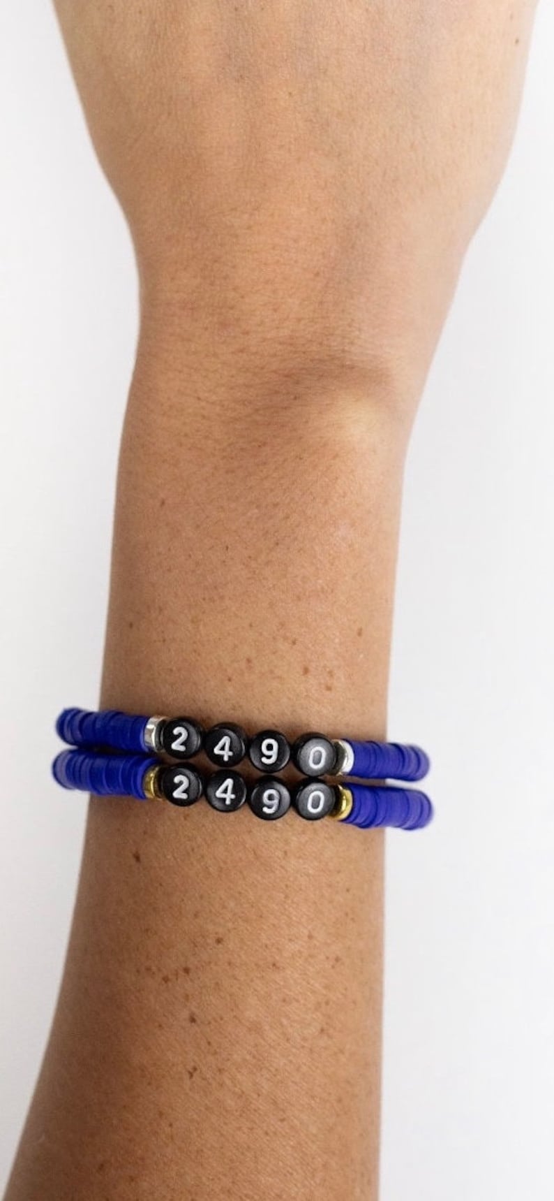 May include: Two blue beaded bracelets with black beads that have the numbers 2490 on them.