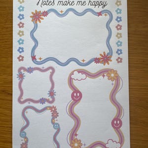 May include: A white sheet of paper featuring four decorative frames with wavy edges. The frames are adorned with flowers, stars, and smiley faces. The text "Notes make me happy" is written at the top in a playful font.