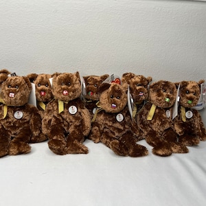 May include: A group of 10 brown teddy bears with different colored patches on their chests. The bears are all wearing yellow ribbons around their necks.