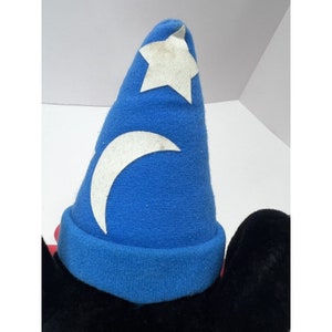 May include: A plush Mickey Mouse toy wearing a blue sorcerer's hat with a white crescent moon and star design.