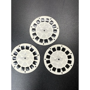 May include: Three circular white View-Master reels for the Walt Disney production Bedknobs & Broomsticks. Each reel features seven pairs of black film frames arranged around the perimeter with printed text in the center identifying the reel number.