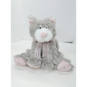 May include: A plush gray cat with pink accents, including ears, paws, and a nose. The stuffed animal has a white muzzle and a pink striped bow. The cat is sitting upright, with its legs extended.