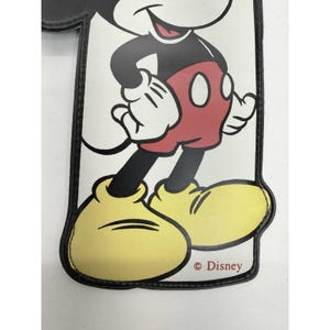 May include: A rectangular, white and black accessory featuring a smiling Mickey Mouse illustration. Mickey is wearing red shorts, yellow shoes, and white gloves. The Disney logo is printed at the bottom.