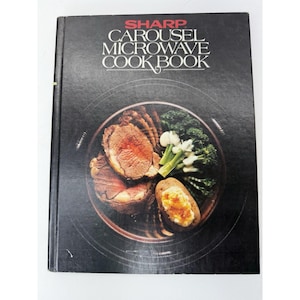 May include: A vintage "Sharp Carousel Microwave Cookbook" with a black cover. The cover features the title in white and red lettering, and an image of a plate of food, including roasted meat, broccoli, and a baked potato.