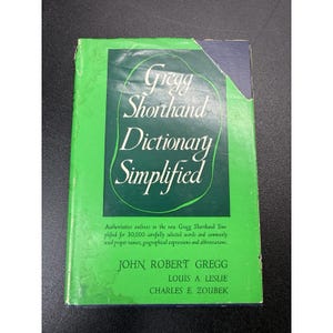 May include: A book titled Gregg Shorthand Dictionary Simplified with a bright green cover and a dark green central panel. The text includes the authors John Robert Gregg, Louis A. Leslie, and Charles E. Zoubek, along with descriptive subtitle text.