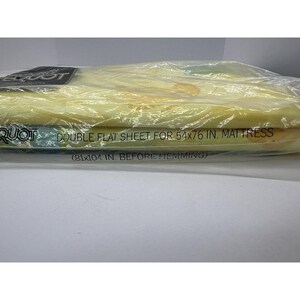 May include: A yellow flat sheet packaged in plastic. The packaging has the text "QUOT DOUBLE FLAT SHEET FOR 54x76 IN. MAT TRESS (81x104 IN. BEFORE HEMMING)"