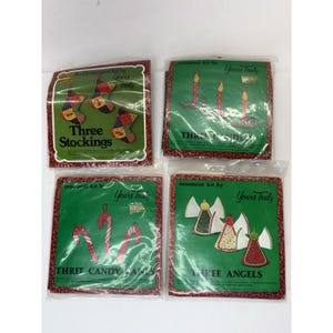 May include: Four vintage ornament kits by "Yours Truly" are displayed. Each kit features a green background with a different holiday design: three stockings, three candles, three candy canes, and three angels. The kits are packaged in clear plastic.