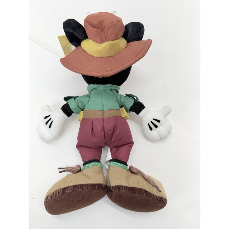 K&ouml;nnte beinhalten: Pl&uuml;schtier einer Zeichentrickfigur mit einem rostfarbenen Hut mit gelbem Band, einem gr&uuml;nen Hemd und weinroten Hosen. Die Figur hat schwarze Ohren, wei&szlig;e Handschuhe und braune Schuhe. Ein Sammlerst&uuml;ck.