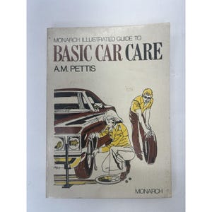 May include: A vintage illustrated guide to basic car care by A.M. Pettis. The cover features a brown car with a person changing a tire and another person looking on. The book is titled "Monarch Illustrated Guide to Basic Car Care" and the author is A.M. Pettis.