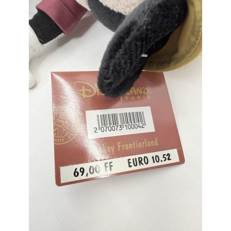 K&ouml;nnte beinhalten: Ein Mickey Mouse Stofftier mit braunem Hut und schwarzen Ohren. Ein Disney Land Paris-Etikett ist angebracht. Das Etikett hat einen Barcode und den Text "Key Frontierland".