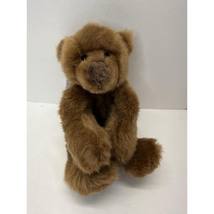 May include: A brown teddy bear with a soft, plush fur texture. The bear is sitting upright with its arms and legs extended. It has a small, round nose and dark eyes. The bear is a classic toy.