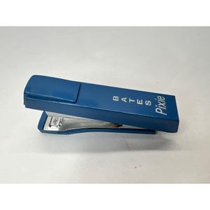May include: A blue metal stapler with the words "Bates Pixie" printed on the top.