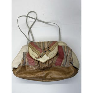 May include: A vintage shoulder bag with a multi-colored design. The bag features a flap closure with a decorative jeweled accent. The body of the bag is made of various textured materials in shades of brown, pink, beige, and gray, with a gray shoulder strap.