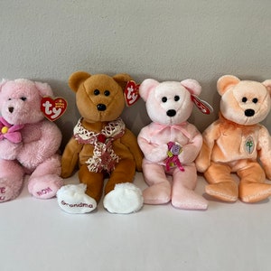 May include: Four plush beanie baby bears in pink, brown, and peach colors. The bears are holding flowers and have embroidered text on their feet that says "Love You", "Mom", "Grandma", and "Happy Mother's Day".