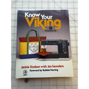 May include: A book titled "Know Your Viking" with a Husqvarna logo. The cover features a sewing machine, a colorful tote bag, and text. The book is by Jackie Dodson with Jan Saunders, foreword by Robbie Fanning.