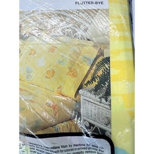 May include: Yellow and white striped packaging with the text "FLUTTER-BYE" at the top. The packaging shows a yellow bedspread with a butterfly pattern and a white wicker bedside table.