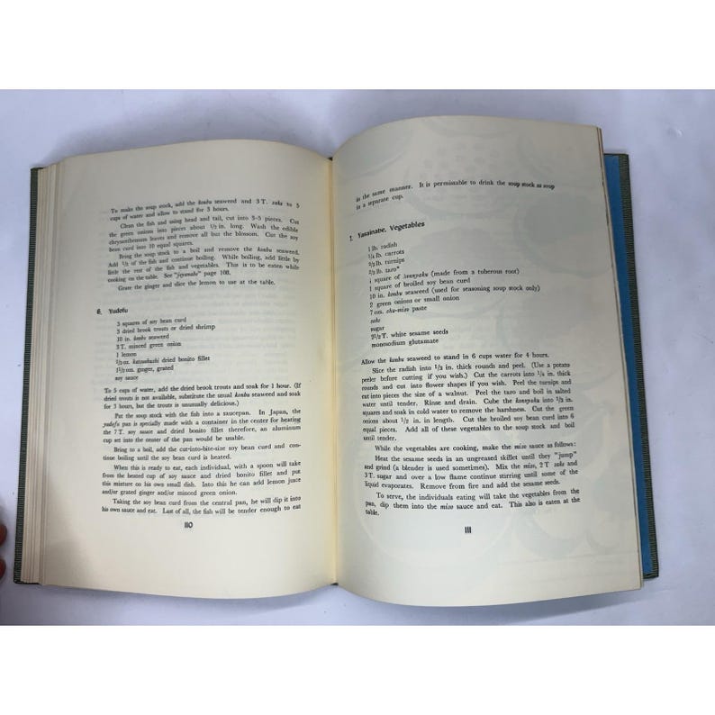 May include: An open cookbook with text on the pages. The left page has a list of ingredients, and the right page has instructions for a recipe. The book is bound with a blue cover.
