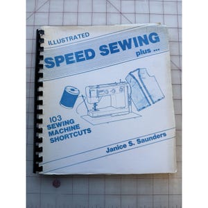 May include: An illustrated book titled "Speed Sewing plus..." with a spiral binding. The cover features blue text and illustrations of a sewing machine, thread spool, and garment pieces. The book is by Janice S. Saunders and contains 103 sewing machine shortcuts.