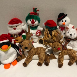 May include: A collection of eight plush toys, including a penguin, a snowman, a reindeer, and Santa Claus, all dressed in festive Christmas attire.