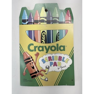 May include: A Crayola Scribble Pad set featuring a pack of colorful crayons. The packaging is yellow and green, with the Crayola logo and a cartoon crayon character. The set includes crayons in various colors, perfect for drawing and coloring.