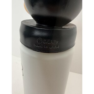 May include: A white and black Disney-branded tumbler. The tumbler has a black lid and a white body. The text "&copy; DISNEY MADE IN CHINA" is printed on the lid. The tumbler appears to be made of plastic.