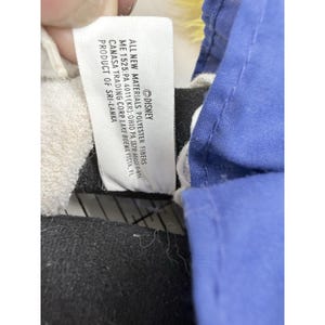 May include: Close-up of a Disney product tag. The tag reads "ALL NEW MATERIALS POLYESTER FIBERS" and includes the Disney logo. The tag also lists the manufacturer and the product's origin in Sri Lanka.
