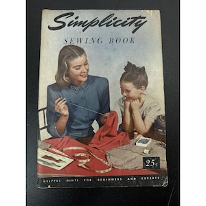May include: A vintage Simplicity Sewing Book with a cover illustration of a person in a blue shirt sewing red fabric while a child watches. The cover features the text Simplicity Sewing Book, Helpful Hints for Beginners and Experts, and 25c.
