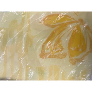 May include: A yellow and orange floral pattern on a white background. The fabric is wrapped in clear plastic.