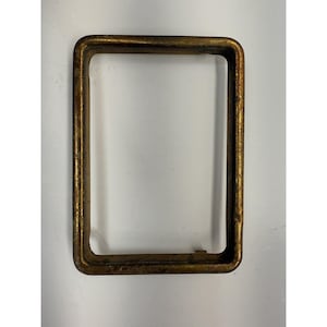 May include: A rectangular metal frame with rounded corners. The frame has a tarnished gold finish, showing signs of wear and age. The object is set against a plain white background, highlighting its shape and texture.