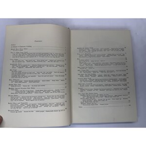 May include: Open cookbook with a table of contents. The pages are off-white with black text. The left page lists Japanese cooking topics like soups and boiled dishes. The right page lists fried foods and rice dishes.