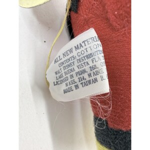 Puede incluir: Primer plano de un peluche con una etiqueta. La etiqueta dice "ALL NEW MATERIAL, CONTENTS: COTTON, WALT DISNEY DISTRIBUTIN, LAKE BUENA VISTA FLA, LICENSED IN PENN. 268. OI, MASS. 214. MAINE, MADE IN TAIWAN IL."
