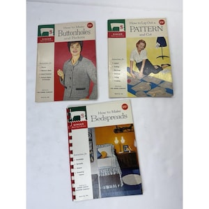 May include: Three vintage Singer Sewing Library books. Titles include "How to Make Buttonholes and Pockets", "How to Lay Out a Pattern and Cut", and "How to Make Bedspreads". Each book features colorful illustrations and text.
