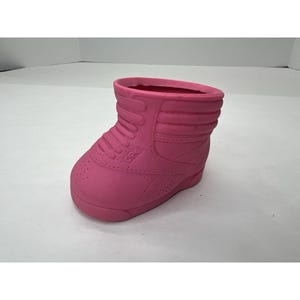 May include: A pink rubber shoe planter. The shoe is a high-top style with a lace-up design.