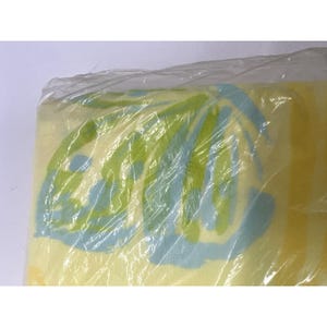 May include: A yellow, green and blue patterned blanket wrapped in plastic.