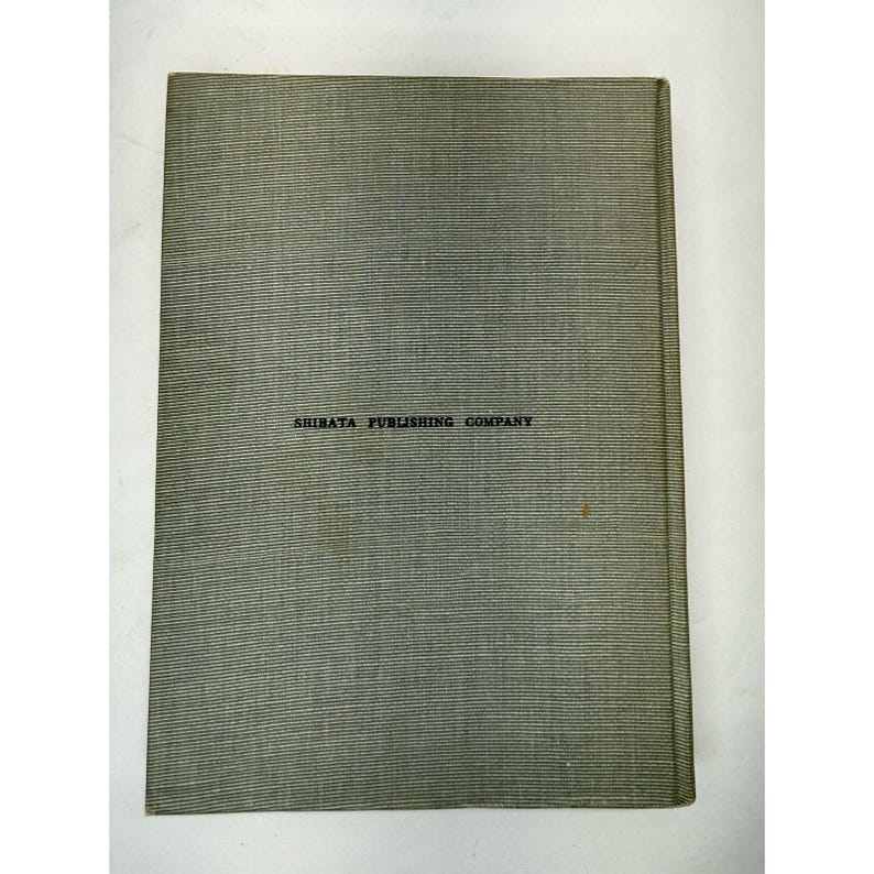 May include: A vintage book cover with a textured, gray-green surface. The text "SHIBATA PUBLISHING COMPANY" is printed in black across the center. The book's spine is visible on the right side.