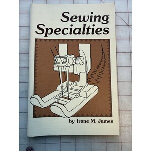 May include: A book titled "Sewing Specialties" by Irene M. James. The cover features a brown square with a detailed illustration of a sewing machine foot. The text is in black, with the title in a large, bold font.