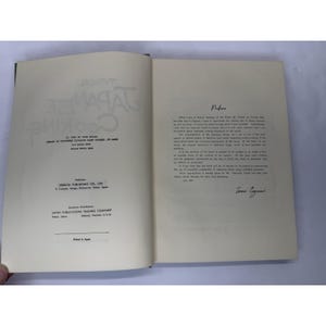 May include: An open book with the title "Typical Japanese Cooking" in large, stylized letters. The left page displays publishing information, while the right page features a preface. The book is cream-colored with black text.