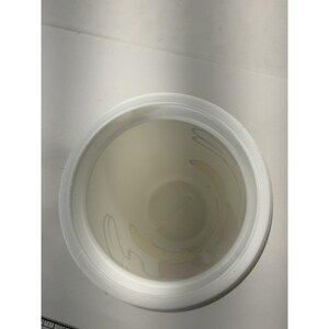 May include: An overhead view of a white plastic container with a wide rim. The interior of the container is off-white with a faint floral design. The container is sitting on a white surface.