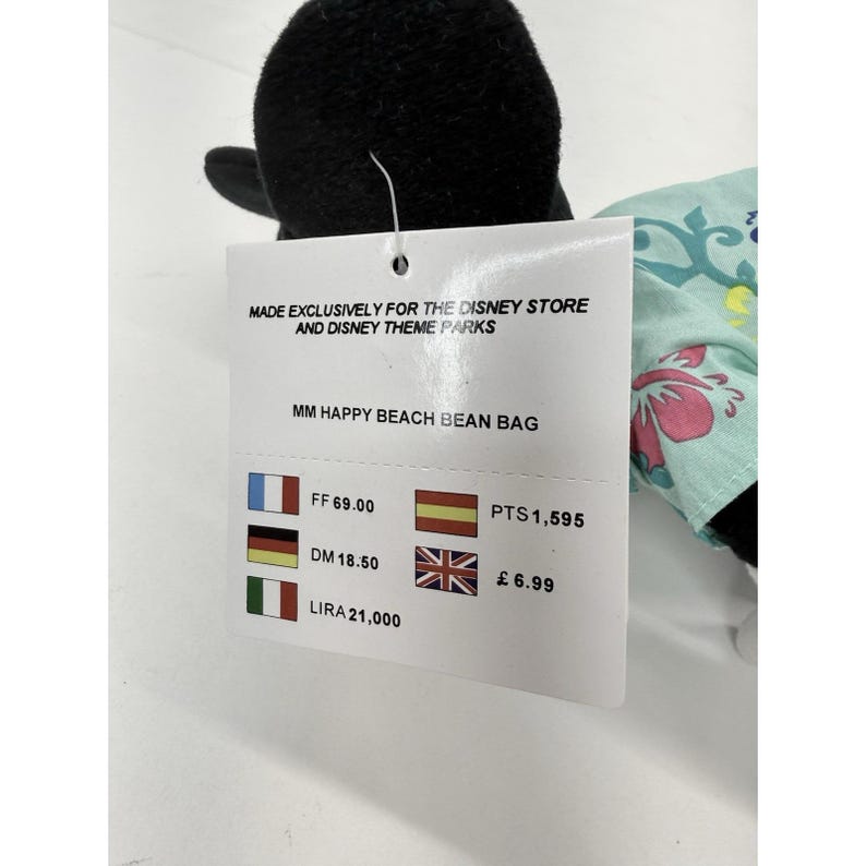 May include: A black plush toy with a tag that reads "MADE EXCLUSIVELY FOR THE DISNEY STORE AND DISNEY THEME PARKS" and "MM HAPPY BEACH BEAN BAG". The tag also displays various currency amounts.