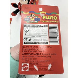 Puede incluir: Un paquete rojo del juguete Pluto Cuddly Collectible con informaci&oacute;n para el consumidor y detalles de seguridad. El paquete incluye el texto "Mickey's Stuff for Kids" y "Made in China."
