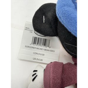 May include: A Sorcerer Mickey Bean Bag plush toy with a blue hat, black ears, and white gloves. The attached tag reads "SORCERER MICKEY BEAN BAG". The tag also includes a barcode and the text "MADE EXCLUSIVELY FOR".