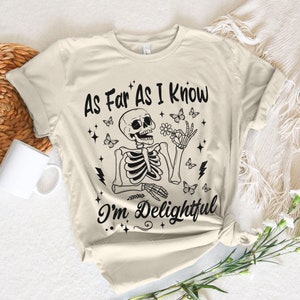 May include: A beige t-shirt with a black skeleton graphic and the text "As Far As I Know I'm Delightful".