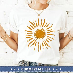 May include: White t-shirt with a distressed orange sun graphic. The sun has a circle in the center and rays extending outward.