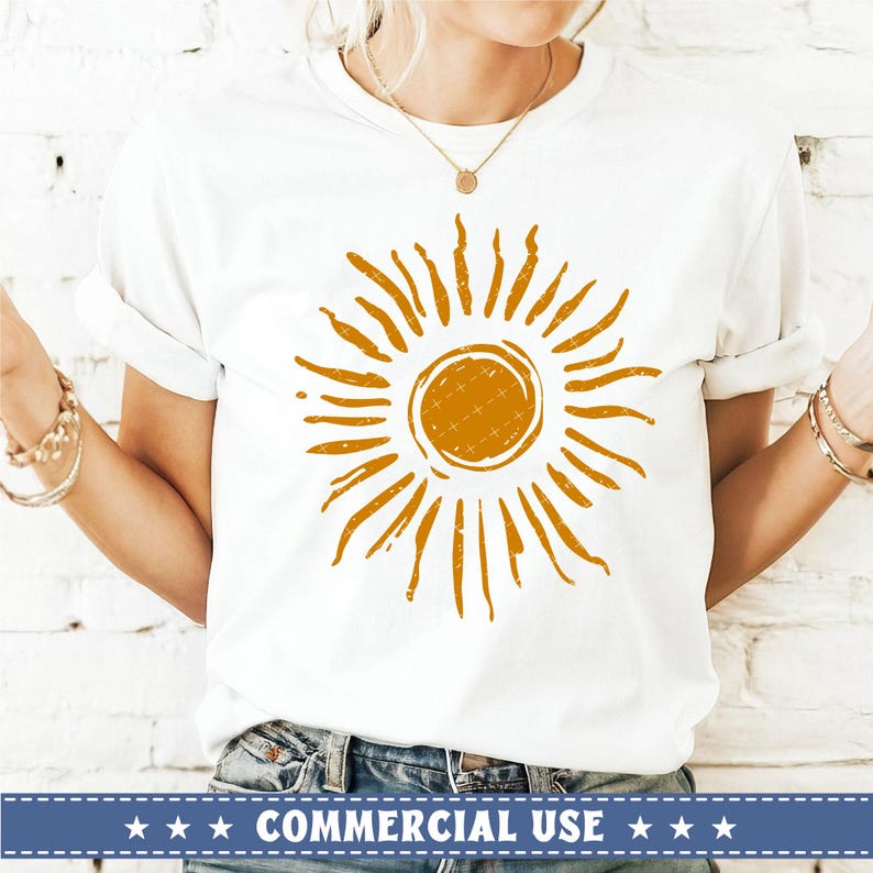 May include: White t-shirt with a distressed orange sun graphic. The sun has a circle in the center and rays extending outward.